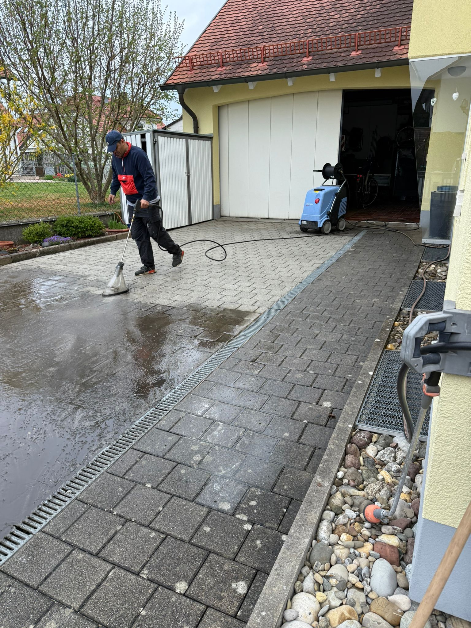 Garageneinfahrt während der Steinreinigung mit Flächenreiniger